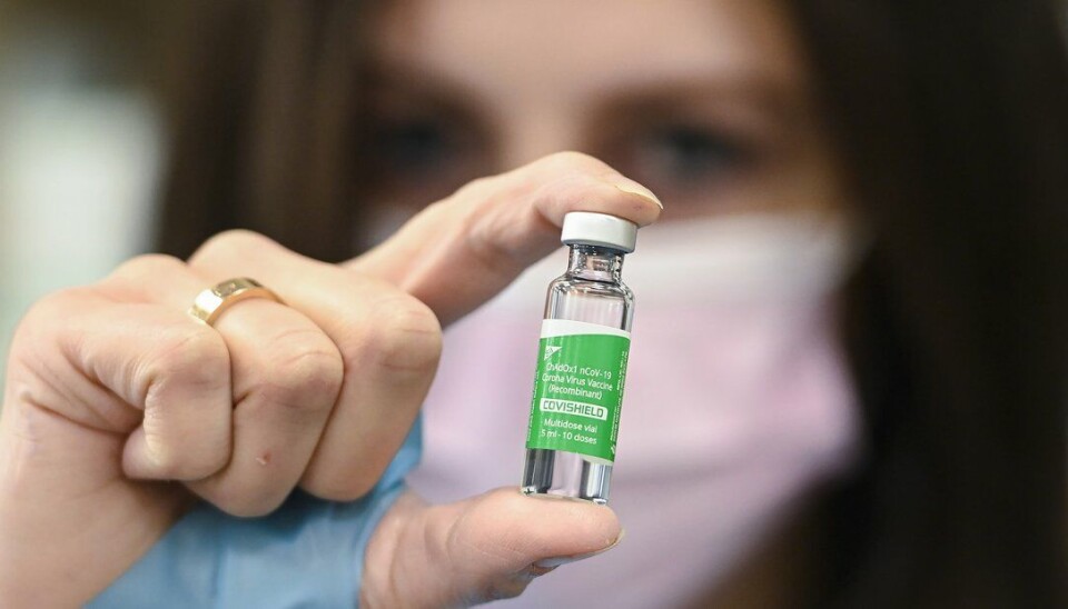 En farmasøyt viser fram et glass med AstraZenecas covid-19-vaksine. Selskapet skriver lørdag kveld at analyser så langt ikke viser noen økt risiko for blodpropp ved bruk av vaksinen.
